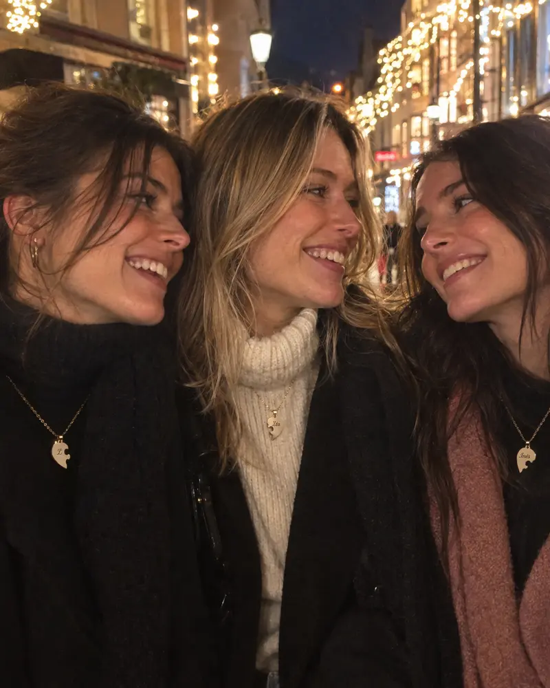 Trois amies dans une rue illuminée pour Noël, chacune porte sa pièce du cœur