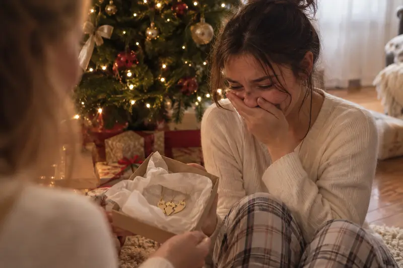 Une jeune femme, émue, découvre les colliers au pied du sapin